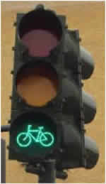 Figure 5 is a photograph of a three-section bicycle signal face. The bottom section shows a green bike symbol signal indication facing to the left.
