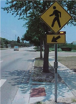 An image diplaying an example of Rectangular Rapid Flashing Beacons with W1-2 sign and W16-7p plaque at crosswalk across uncontrolled approach. [Photo courtesy of City of St. Petersburg, Florida]
