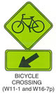 Pedestrian and Bicycle Sign "BICYCLE CROSSING (W11-1)" Is shown again with W16-7p sign shown directly below it. W16-7p is shown as a horizontal rectangular green sign with a black border. It shows a diagonal black arrow pointing down and to the left.