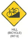 Pedestrian and Bicycle Sign "HILL (BICYCLE) (W7-5)" is shown as a diamond-shaped yellow sign with a black border. It shows a black symbol of a bicycle pointing to the left and down on a ramp that slopes up from left to right.