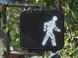 Shows a pedestrian signal face with the white walking person indication illuminated.