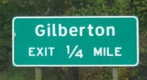 the image is of a road sign with a green background and white lettering.  It reads: Gilberton EXIT 1/4 MILE.  The four is lower than the 1.