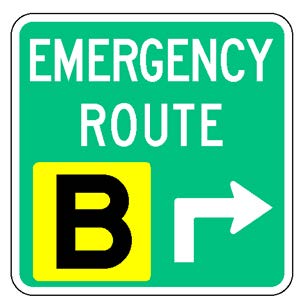 A square single sign with a green background color.  The legend reads "Emergency Route" in white letters at the top of the sign below which is a white directional arrow and a black upper-case "B" in a yellow square background panel to its left to identify the route.