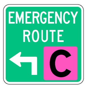 A square single sign with a green background color.  The legend reads "Emergency Route" in white letters at the top of the sign below which is a white directional arrow and a black upper-case "C" in a fluorescent pink square background panel to its right to identify the route.