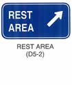 Motorist Services and Recreation Sign "REST AREA (D5-2)" is shown as a horizontal rectangular sign with the words "REST AREA" on two lines and, to the right of the text, a diagonal arrow pointing up and to the right.