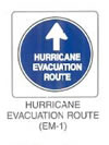 Guide Sign "HURRICANE EVACUATION ROUTE (EM-1)" is shown as a square sign with a blue circular disk on which are shown a white arrow and white lettering. A vertical upward-pointing white arrow is shown above the words "HURRICANE EVACUATION ROUTE" shown on three lines. An asterisk to the right of the sign is denoted as "HURRICANE is an example of one type of evacuation route. Legends for other types may also be used, or this line of text may be omitted."