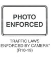 Regulatory Sign "TRAFFIC LAWS ENFORCED BY CAMERA (R10-19)" is shown as a horizontal rectangular white sign with a black border and the words "PHOTO ENFORCED" in black on two lines. This sign was anticipated for inclusion in the 2003 edition of the MUTCD at the time of this printing.