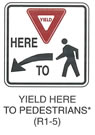 Pedestrian and Bicycle Sign "YIELD HERE TO PEDESTRIANS (R1-5)" is shown as a square white sign with a black border. A Yield sign is shown above the word "HERE," which is above a horizontal black arrow curving down and to the left above the word "TO." A black walking person symbol is shown to the right of the arrow. This sign was anticipated for inclusion in the 2003 edition of the MUTCD at the time of this printing.